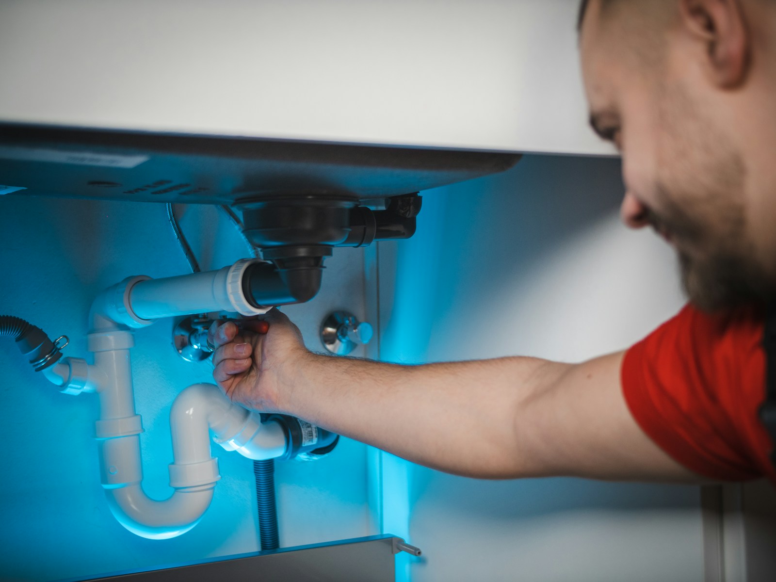 Licensed emergency plumber actively repairing a pipe at a DFW home